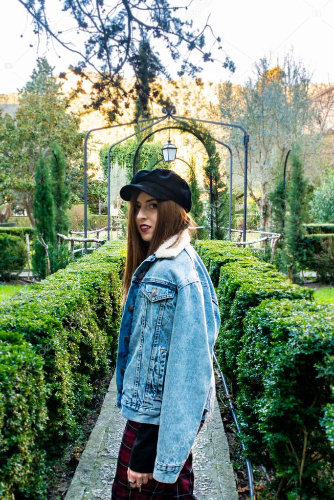 Profile portrait, of a pretty young girl wearing a denim jacket and a black beret, in the gardens of the Valldemossa Charterhouse, Tramontana Majorcan area