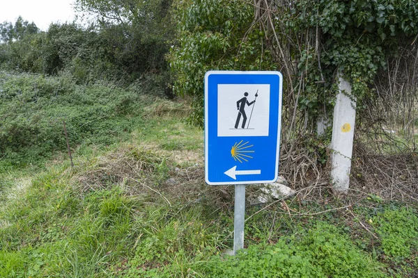 Typical signage that indicates the direction to follow on the Camino de Santiago, blue background and a yellow scallop. Traditional pilgrimage of Christianity in northern Spain