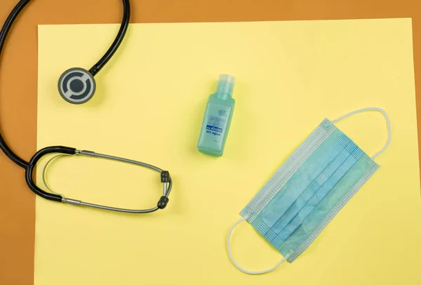 Medical utensils kit: a stethoscope, a mask and a hands cleaning. Text in spanish: Gel hand cleaner with alcohol, without water.