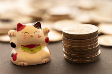 Maneki neko ya da bozuk para yığını ile işaret eden, ve arka planda daha fazla odaklanmamış bozuk para.. Şansın, bolluğun ve ekonomik başarının kavramsal sembolü.