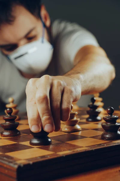 Social distancing in the 2019-ncov or coronavirus crisis. A man in a medical mask moves a token on a chess board full of pawns