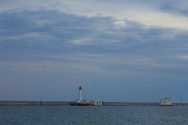 Güzel manzara. Mevcut deniz feneri. Odessa 'daki Vorontsov deniz fenerine karşı Karadeniz' in arka planı, yakın plan. Üzerinde mavi deniz manzaralı kırmızı bir kabin olan beyaz kule.