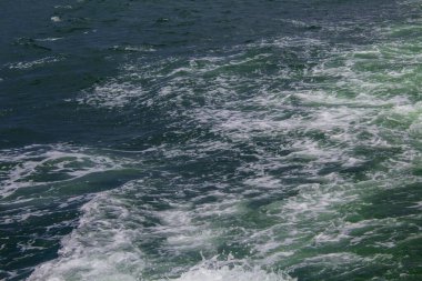 Güneş ışığının yansıttığı güzel bir gölün mavi suyu başlıyor. Deniz suyu yüzeyi. Mavi okyanusun doğa arka planı, en üst manzara.