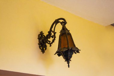 Sarı duvarda, dış tarafta klasik metal lamba.