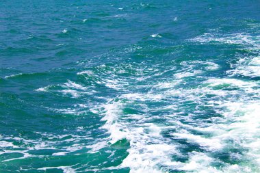 Güneş ışığının yansıttığı güzel bir gölün mavi suyu başlıyor. Deniz suyu yüzeyi. Mavi okyanusun doğa arka planı, en üst manzara.