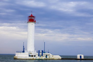 Güzel manzara. Mevcut deniz feneri. Odessa 'daki Vorontsov deniz fenerine karşı Karadeniz' in arka planı, yakın plan. Üzerinde mavi deniz manzaralı kırmızı bir kabin olan beyaz kule.