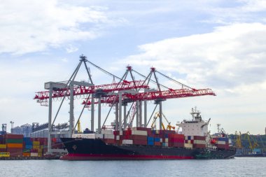 Odessa, Karadeniz 'deki akşam limanında portallar. Denize yanaşmış ağır bir yük gemisi. Arka planda konut ve ticari binalar bulunmaktadır.