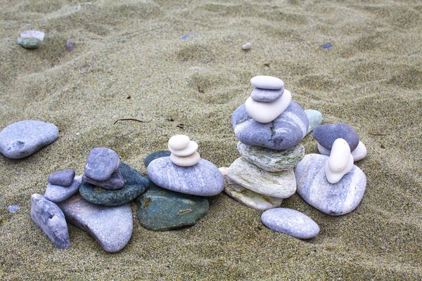 zen stone on sand, pebble art , small flat stones carefully placed together, conceptually, to resemble a pyramid form