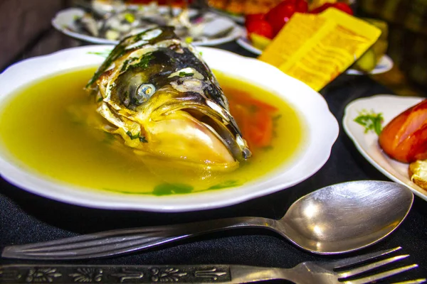 Fish soup with fish head in a plate on table