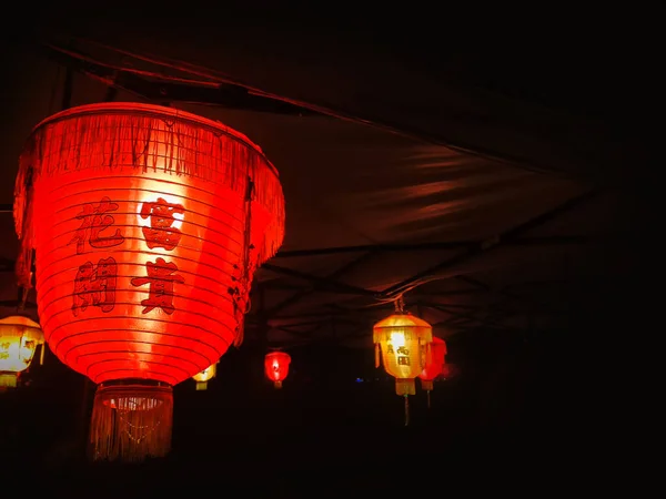 Chinese red lanterns in the park. Retro style lantern at night. Beautiful colorful illuminated lamp in the garden.