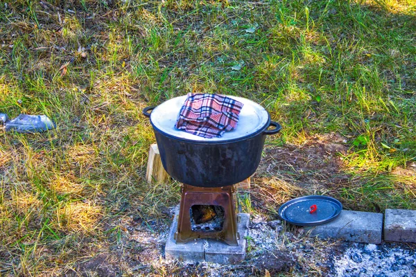kettle with food camping. camping food - barbeque outdoor in summer camp. Hot big wok pan on the fire in the forest. camping food - barbeque outdoor in summer camp.Burning foldable wood stove