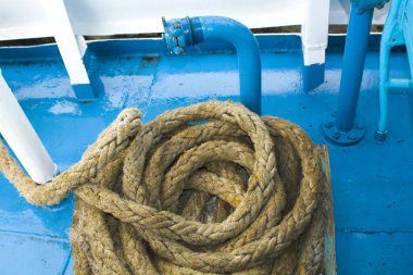 Yıpranmış eski bir halat, bir körfeze yuvarlanmış, bir teknede yatıyor. Limandaki bir yelkenli gemisinin sabit halatı.
