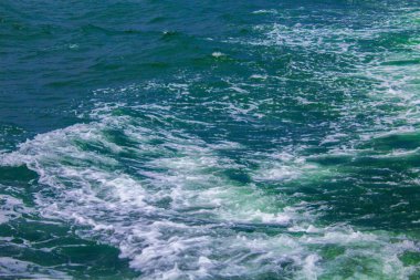 Güneş ışığının yansıttığı güzel bir gölün mavi suyu başlıyor. Deniz suyu yüzeyi. Mavi okyanusun doğa arka planı, en üst manzara.