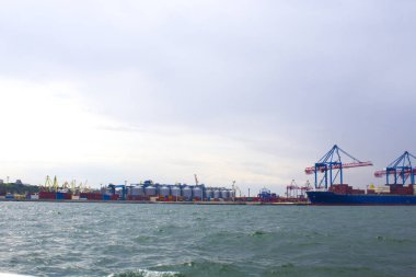 Odessa, Karadeniz 'deki akşam limanında portallar. Denize yanaşmış ağır bir yük gemisi. Arka planda konut ve ticari binalar bulunmaktadır.