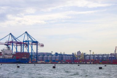 Odessa, Karadeniz 'deki akşam limanında portallar. Denize yanaşmış ağır bir yük gemisi. Arka planda konut ve ticari binalar bulunmaktadır.