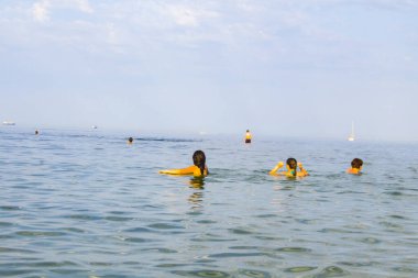 İnsanlar Karadeniz 'in sularının keyfini çıkarıyorlar. Birçok insan deniz suyunda yüzer. Karadeniz 'de tatil yapan turistler.
