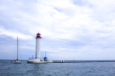 Güzel manzara. Mevcut deniz feneri. Odessa 'daki Vorontsov deniz fenerine karşı Karadeniz' in arka planı, yakın plan. Üzerinde mavi deniz manzaralı kırmızı bir kabin olan beyaz kule.