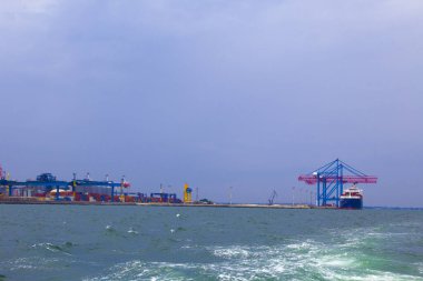 Odessa, Karadeniz 'deki akşam limanında portallar. Denize yanaşmış ağır bir yük gemisi. Arka planda konut ve ticari binalar bulunmaktadır.