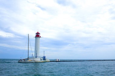 Güzel manzara. Mevcut deniz feneri. Odessa 'daki Vorontsov deniz fenerine karşı Karadeniz' in arka planı, yakın plan. Üzerinde mavi deniz manzaralı kırmızı bir kabin olan beyaz kule.