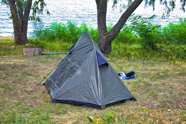 nature landscape camping tent under the tree on green grass meadow or park with lake or river  for picnic travel on family vacation and holiday relax