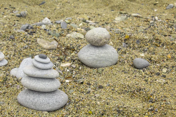 zen stone on sand, pebble art , small flat stones carefully placed together, conceptually, to resemble a pyramid form