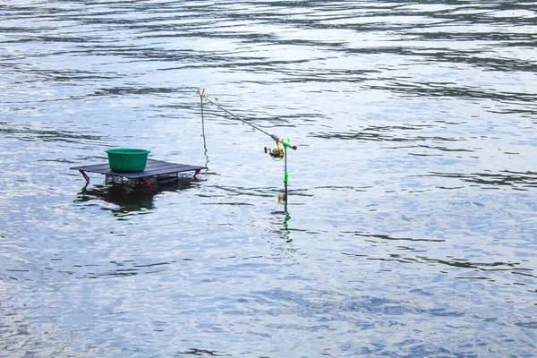 Fishing with feeder fishing rod on river, view from place of fisherman during fishing. Fishing rod on the water without man. Lake and still water