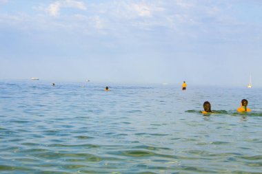 İnsanlar Karadeniz 'in sularının keyfini çıkarıyorlar. Birçok insan deniz suyunda yüzer. Karadeniz 'de tatil yapan turistler.