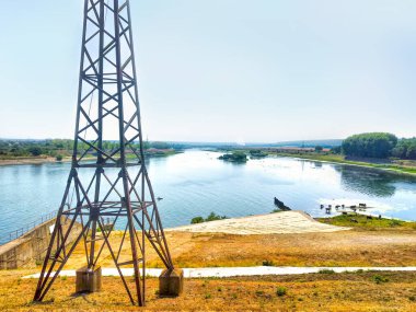 Gökyüzü arka planında yüksek voltajlı elektrik kulesi hattı, pilonun günbatımı silueti.