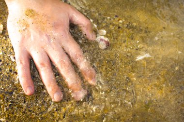  Eller arka planda, yakın plan. Kumsalda kumları tutan eller