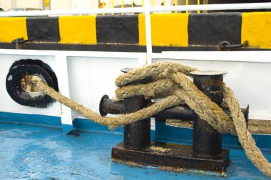 Yıpranmış eski bir halat, bir körfeze yuvarlanmış, bir teknede yatıyor. Limandaki bir yelkenli gemisinin sabit halatı.