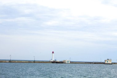 Güzel manzara. Mevcut deniz feneri. Odessa 'daki Vorontsov deniz fenerine karşı Karadeniz' in arka planı, yakın plan. Üzerinde mavi deniz manzaralı kırmızı bir kabin olan beyaz kule.