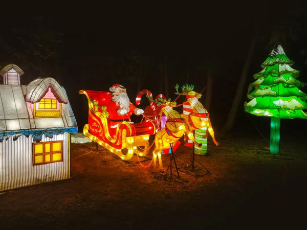 Illuminated lighting figure of Santa Claus, night time at Christmas festival in winter season. A composition of light bulbs depicting a Christmas deer and sleigh.