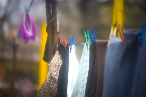 Clothes hanging out to dry in the sun on a washing line with plastic clothespins. Selective focus.