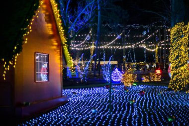 Noel ışıkları müesseseden. Çatının altında asılı sarı, kırmızı, turuncu ampullerden oluşan su geçirmez güzel bir çelenk. Parlayan güzel Noel ağaçları