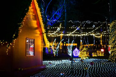 Noel ışıkları müesseseden. Çatının altında asılı sarı, kırmızı, turuncu ampullerden oluşan su geçirmez güzel bir çelenk. Parlayan güzel Noel ağaçları