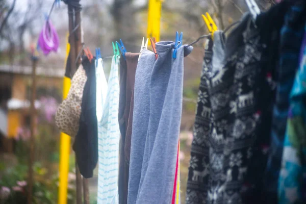 Clothes hanging out to dry in the sun on a washing line with plastic clothespins. Selective focus.