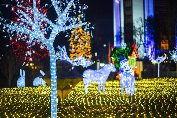 beautiful christmas glowing trees, figures on a city park