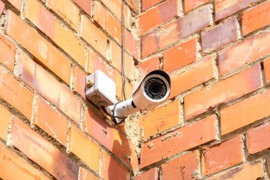 Köşede güvenlik kamerası olan tuğla duvar..