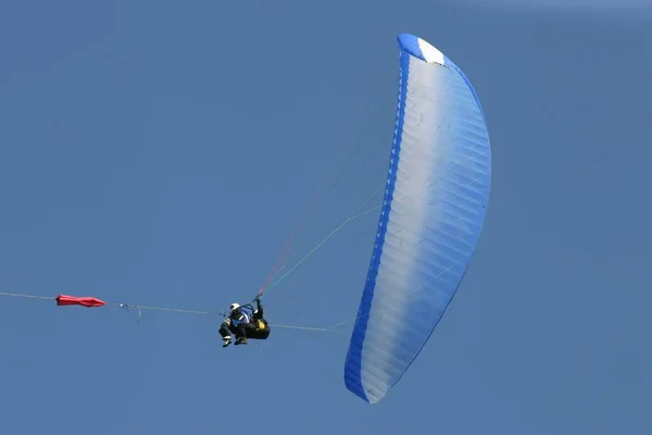 一个穿着蓝色夹克 带着降落伞在天空中飞翔的男人 — 图库照片