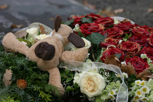 plush and roses on a fresh grave children