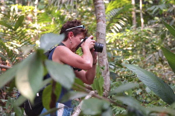 young woman looking for photo opportunities in the tropical rainforest brazil
