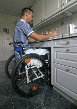 man on wheelchair cooking some food at the kitchen clipart