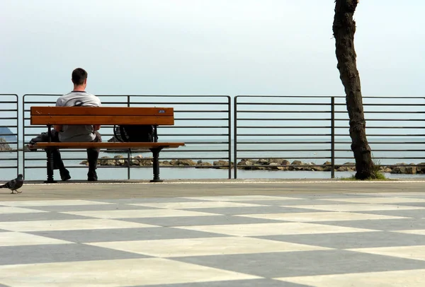 Νεαρός Άνδρας Στην Παραλία Κάθεται Ένα Παγκάκι — Φωτογραφία Αρχείου