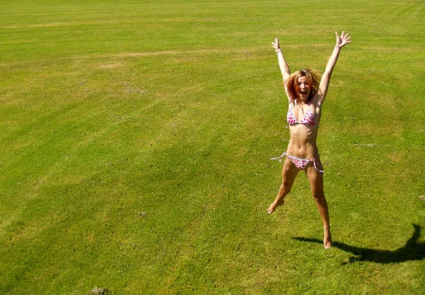 ビキニ姿の若い女性が草の上を飛び — ストック写真