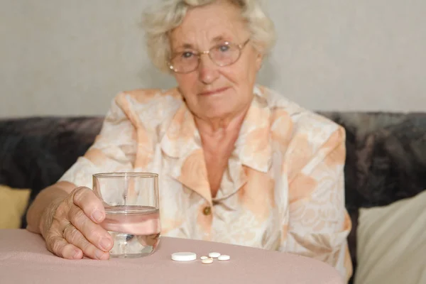 Una Señora Mayor Con Vaso Agua Píldoras Centrarse Las Tabletas Imagen de archivo