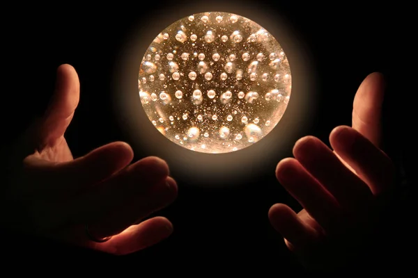 human hand holding glowing sphere with light bulb