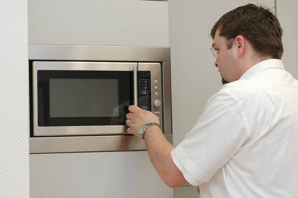 man in kitchen with microwave oven