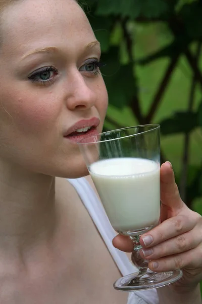 Νεαρή Γυναίκα Πίνει Γάλα Από Ένα Ποτήρι Φρέσκο Πράσινο Γρασίδι — Φωτογραφία Αρχείου