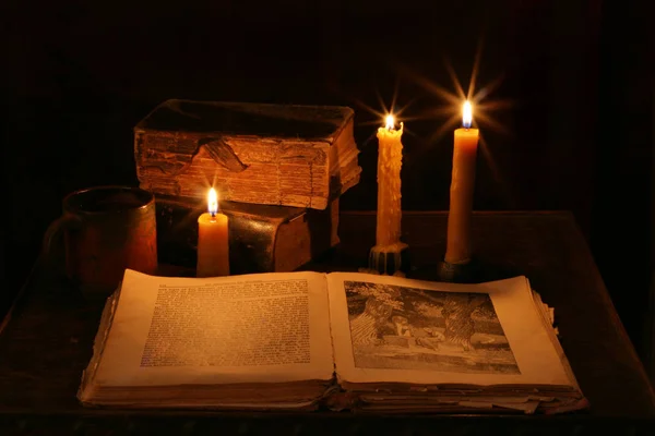 木桌上燃着蜡烛的旧圣经 — 图库照片