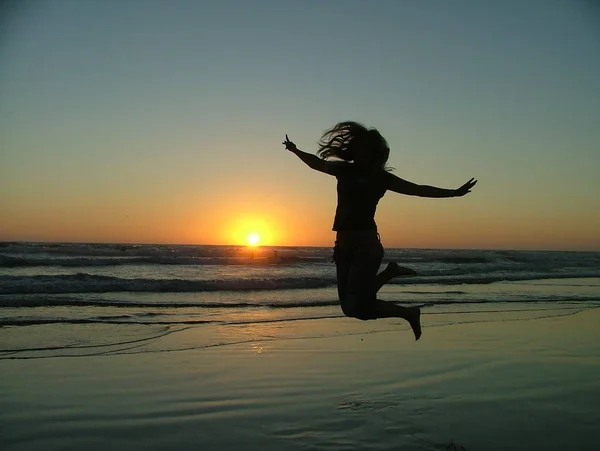 Jonge Vrouw Springen Het Strand Bij Zonsondergang — Stockfoto